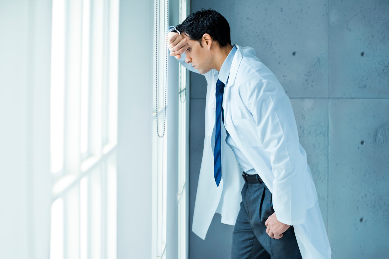 Frustrated doctor leaning on window