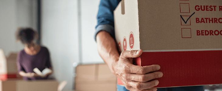 man holding a box and is about to move out of state with a protection order, and with a women reading a book in the background